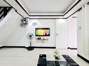 Dieses weiße Zimmer verfügt über einen Flachbild-TV an der Wand. in der Unterkunft Calapan City Fully Furnished House Transient near XentroMall L39 in Calapan