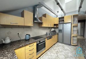 a kitchen with wooden cabinets and a stainless steel refrigerator at ZigZag Room in Gdańsk