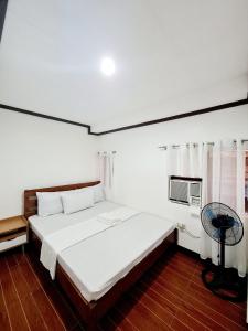 Schlafzimmer mit einem weißen Bett und einem TV in der Unterkunft Calapan City Fully Furnished House Transient near XentroMall L39 in Calapan