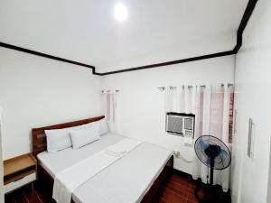 Schlafzimmer mit einem weißen Bett und einem Ventilator in der Unterkunft Calapan City Fully Furnished House Transient near XentroMall L39 in Calapan