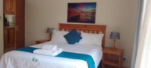 a bedroom with a bed with blue and white pillows at Sand River Cottages in Hazyview