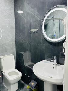 a bathroom with a toilet and a sink and a mirror at KERUEN SARAY APARTMENTS 20/2 in Türkistan