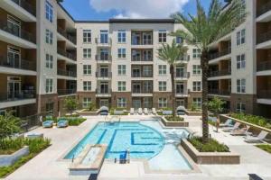 an apartment building with a pool and palm trees at Coolest Luxury Palace Downtown in Houston
