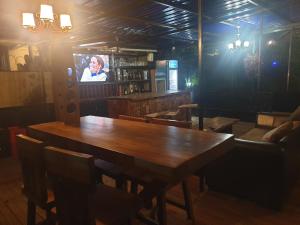 a dining room with a wooden table and a tv at Rosa negra kampala in Kigo