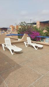 zwei weiße Stühle und eine Rutsche auf einer Terrasse in der Unterkunft Villa Standing bord de mer Club Evasion Tiznit in Mirleft