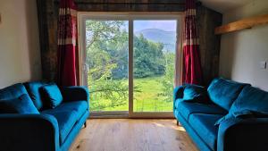 a living room with two blue couches and a large window at Eagle's Nest Connemara and Mayo in Westport