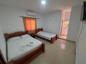 1 dormitorio con 2 camas, TV y ventana en HOTEL LONDON Con Parqueadero en Aguachica