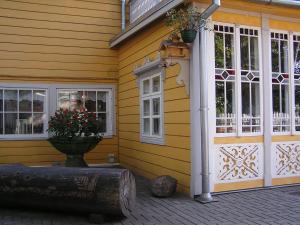 Una casa amarilla con una puerta y flores. en Majoru Promenāde, en Jūrmala