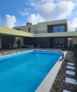 uma casa com piscina em frente a uma casa em Casa Genne em Torres Vedras