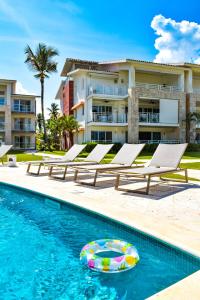 蓬塔卡纳Playa Palmera Beach Resort的大楼前的游泳池,配有躺椅和沙滩球
