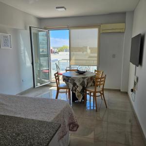 a dining room with a table and chairs and a balcony at BELGRANOPtoMadryn in Puerto Madryn