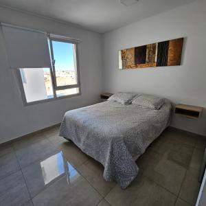 a white bedroom with a bed and a window at BELGRANOPtoMadryn in Puerto Madryn