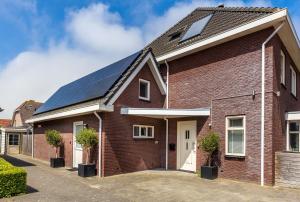 una casa de ladrillo rojo con paneles solares. en Aanloop 22 en Domburg