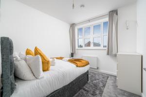 um quarto com uma cama com almofadas amarelas e uma janela em Luxury 2 Bedroom Apartment Free Parking, Netflix, Sleeps 6 em Watford