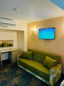 Hotel La Ane في Babadau: غرفة معيشة مع أريكة خضراء وتلفزيون على الحائط