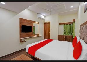 a bedroom with a bed with red pillows and a television at hotel swagat inn in Ahmedabad