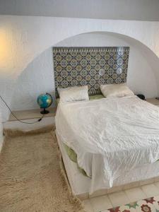 een slaapkamer met een wit bed met een gewatteerd hoofdeinde bij Charming house in Arabesque style in Hammamet Nord