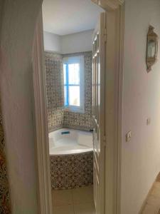 een badkamer met een bad en een raam bij Charming house in Arabesque style in Hammamet Nord