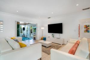 a living room with white furniture and a flat screen tv at Exclusive Miami House: Your Private Pool Paradise in Biscayne Park