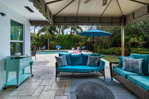 um pátio com sofás azuis, um guarda-sol e uma piscina em Exclusive Miami House: Your Private Pool Paradise em Biscayne Park