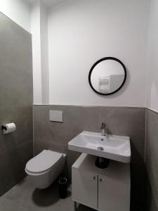 ein Badezimmer mit einem Waschbecken, einem WC und einem Spiegel in der Unterkunft estrella24 LIVING ROOMS Sydney in Herne