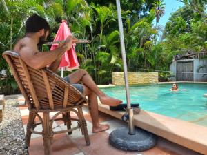 a man sitting in a chair playing a violin by a swimming pool at Nopalero Hostel in Puerto Escondido