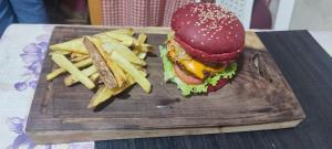 una hamburguesa y papas fritas en una tabla de cortar de madera en Posada del Abuelo en Torotoro