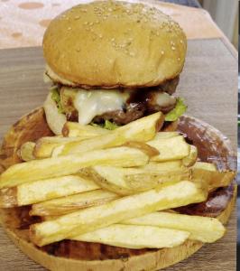 una hamburguesa y papas fritas en una mesa de madera en Posada del Abuelo en Torotoro