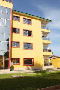 a tall yellow building with windows on the side of it at Akkwa 2 Suites in Kololi