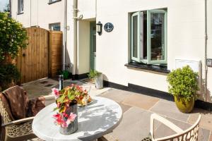 a patio with a table with flowers on it at Cosy Cottage rural village near Tavistock/sleeps 4 in Bere Alston