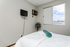 um quarto com uma cama branca e uma janela em Apto em condomínio pé na areia, c/ piscina MHR308 em Florianópolis