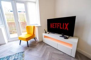 sala de estar con TV y silla amarilla en The Luxury Inn, Birmingham en Birmingham