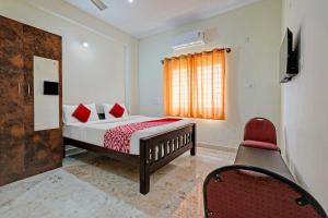 Oyo Flagship Sri Chowdeshwari Boarding And Lodging في بانغالور: غرفة نوم بسرير وكرسي احمر