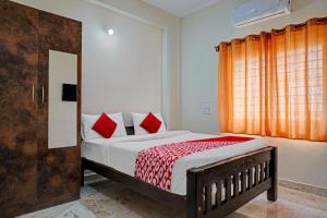Oyo Flagship Sri Chowdeshwari Boarding And Lodging في بانغالور: غرفة نوم بسرير ومخدات حمراء ونافذة