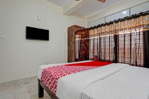 Oyo Flagship Sri Chowdeshwari Boarding And Lodging في بانغالور: غرفة نوم بسرير كبير مع بطانية حمراء