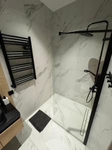 a bathroom with a shower with white marble walls at Chicago Apartment in Katowice