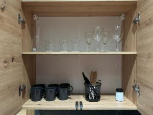 a wooden cabinet with wine glasses and utensils at Chicago Apartment in Katowice