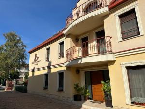 a yellow building with a balcony on a street at Szent Gy&ouml;rgy Villa Apartmanh&aacute;z in H&eacute;v&iacute;z