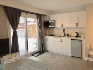 a kitchen with white cabinets and a large sliding glass door at Grandravine/Beautiful Unit near downtown Toronto in Toronto