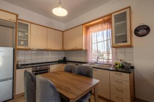 a kitchen with a wooden table with chairs and a refrigerator at Deluxe Apartment LA in Larisa