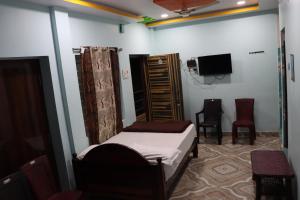 a bedroom with a bed and a tv and chairs at G.M Luxury Hotel in Srīsailam