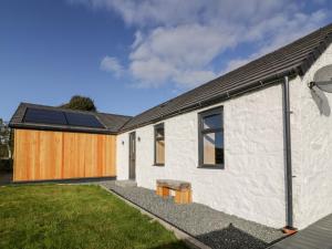 a white house with solar panels on it at Hardhills Cottage in Castle Douglas