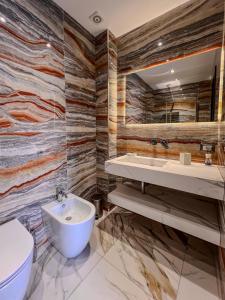 Ricci Palace Suites في كاتانيا: حمام مع مرحاض بالوعة ومرآة