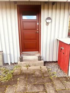 uma porta vermelha ao lado de uma casa em Lejlighed/rækkehus med adgang til pool. em Vipperød