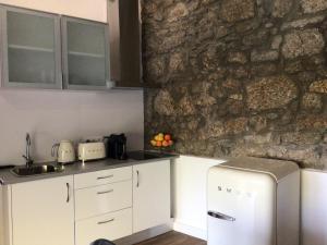 eine Küche mit weißen Schränken und einer Steinmauer in der Unterkunft Casa Do Refugio in Covilhã