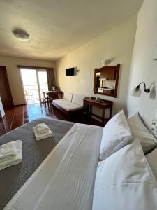 a bedroom with a large white bed and a living room at Iolkos Hotel Apartments in Kato Daratso