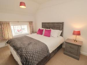 a bedroom with a large bed with pink pillows at Inglenook Cottage in Guisborough