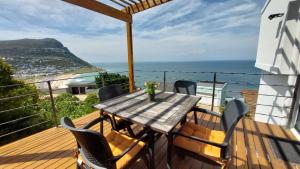 a wooden table and chairs on a balcony with the ocean at A Relaxing Getaway with Ocean Views in Cape Town