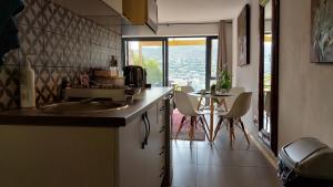 uma cozinha com um lavatório e uma mesa com cadeiras em A Relaxing Getaway with Ocean Views em Cidade do Cabo