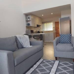 Il comprend un salon doté d'un canapé et d'une chaise ainsi qu'une cuisine. dans l'établissement Cozy Stay, à Windhoek